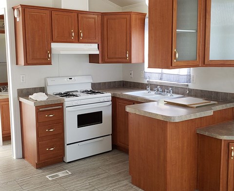 A kitchen with a white stove and wooden cabinets.