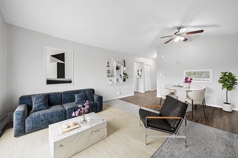 A living room with a blue couch, a white coffee table, and a ceiling fan.