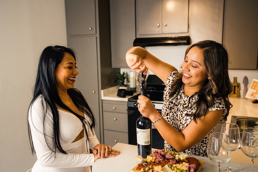 a woman pouring a bottle of wine into another woman