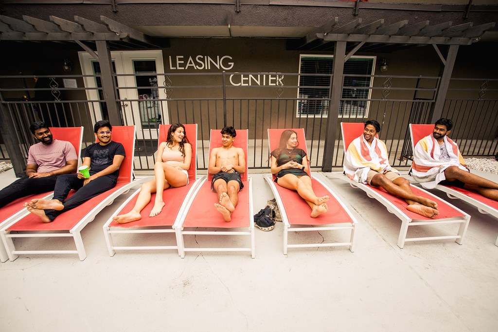 a group lounging on the pool chairs together