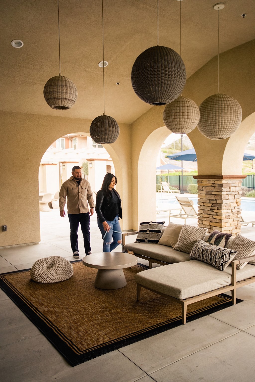 a couple walks through a living room with couches and lamps