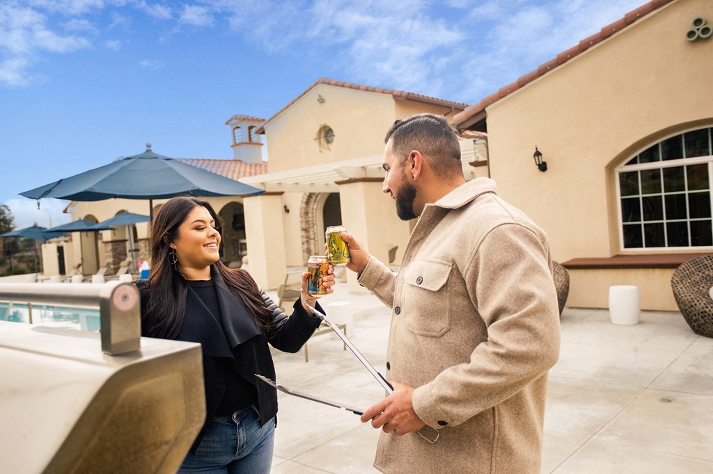 a man giving a woman a bottle of beer outside of a house