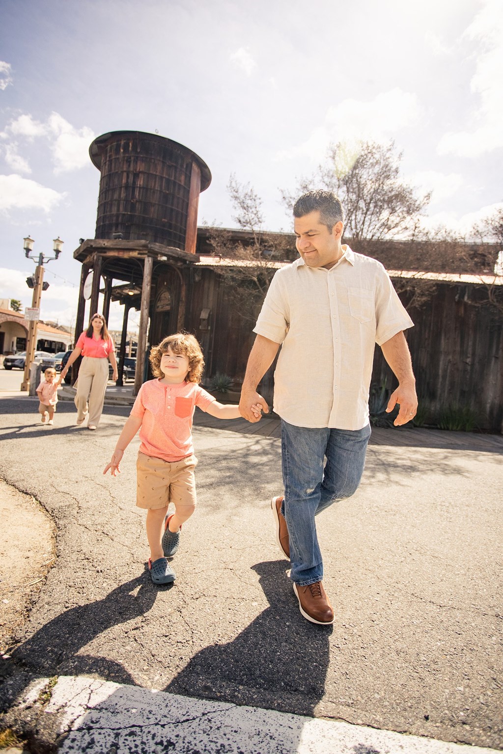a man and a little boy holding hands and walking down the street at Arrive Temecula, Temecula