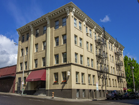 A large beige building with a red awning on the ground floor.