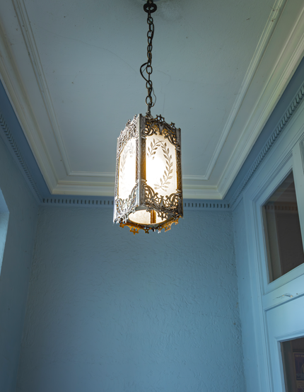 A hanging light fixture with a white and gold design.