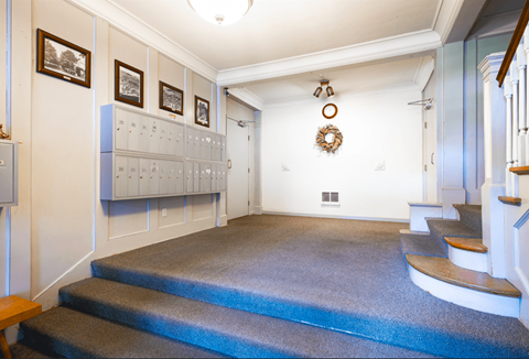 A hallway with a staircase and a wreath on the wall.
