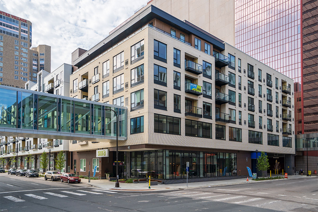 A modern building with a glass entrance and a balcony at Sora Apartments, Minneapolis, MN