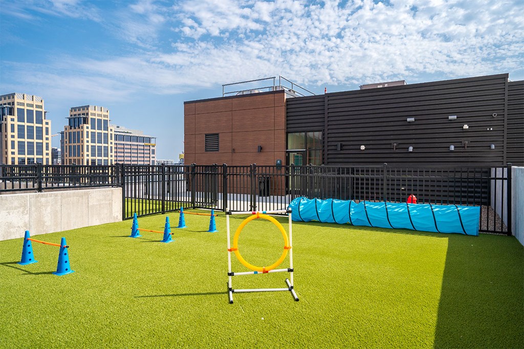 A playground with a blue and green surface, orange cones, and a yellow hoop at Sora Apartments, Minneapolis 55415