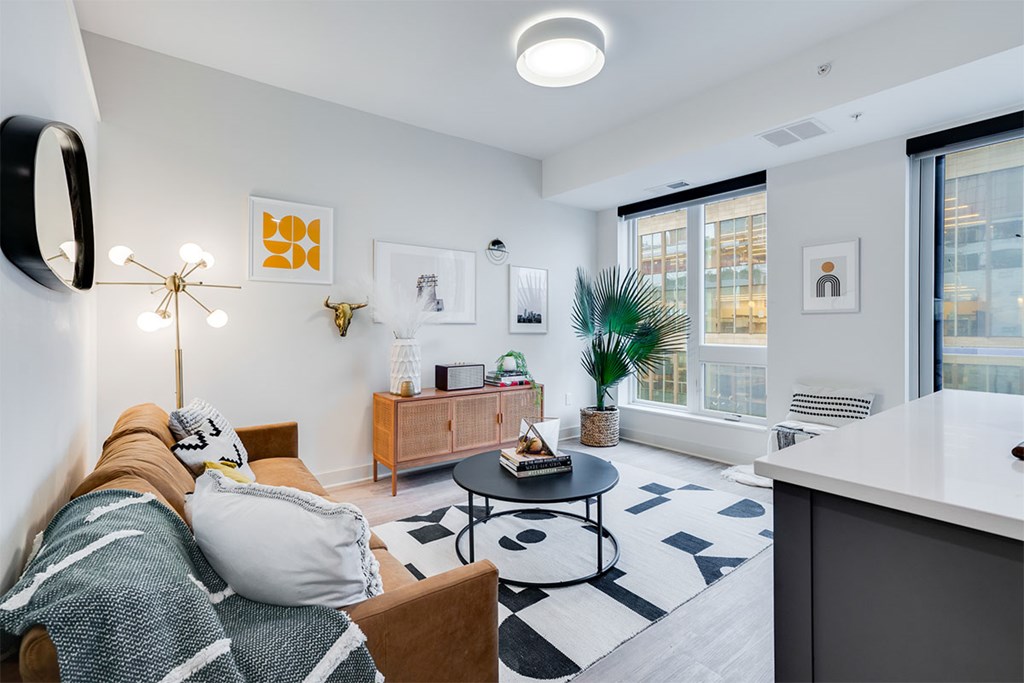 A modern living room with a couch, coffee table, and a large window. at Sora Apartments, Minneapolis 55415