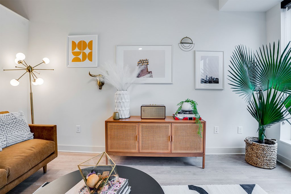 A living room with a brown sofa, a white coffee table, and a green plant. at Sora Apartments, Minneapolis