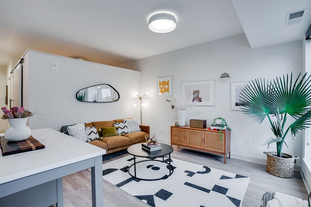 A living room with a white couch, a coffee table, and a plant. at Sora Apartments, Minneapolis 55415