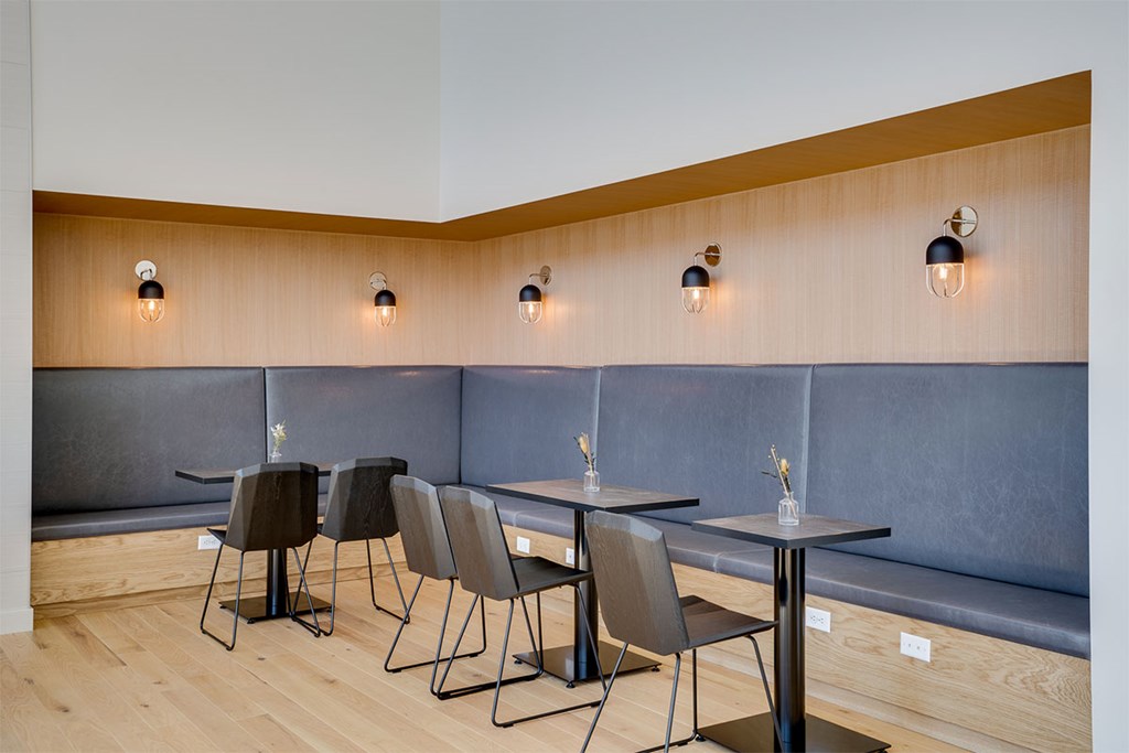 A modern dining area with grey chairs and tables. at Sora Apartments, Minnesota