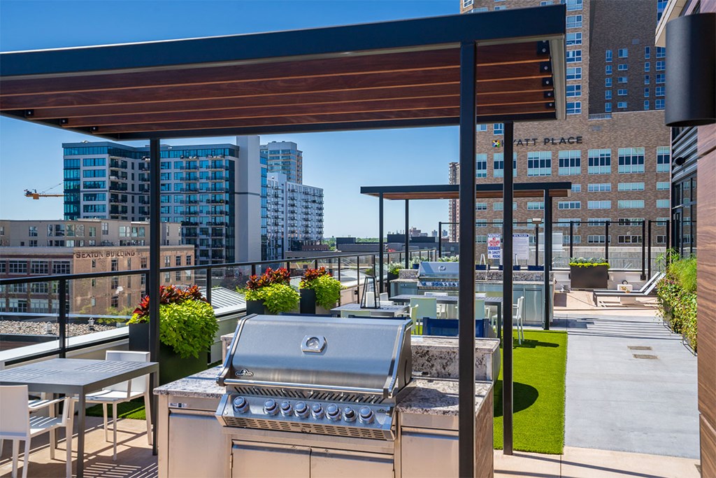 A barbecue grill on a patio with a table and chairs at Sora Apartments, Minnesota
