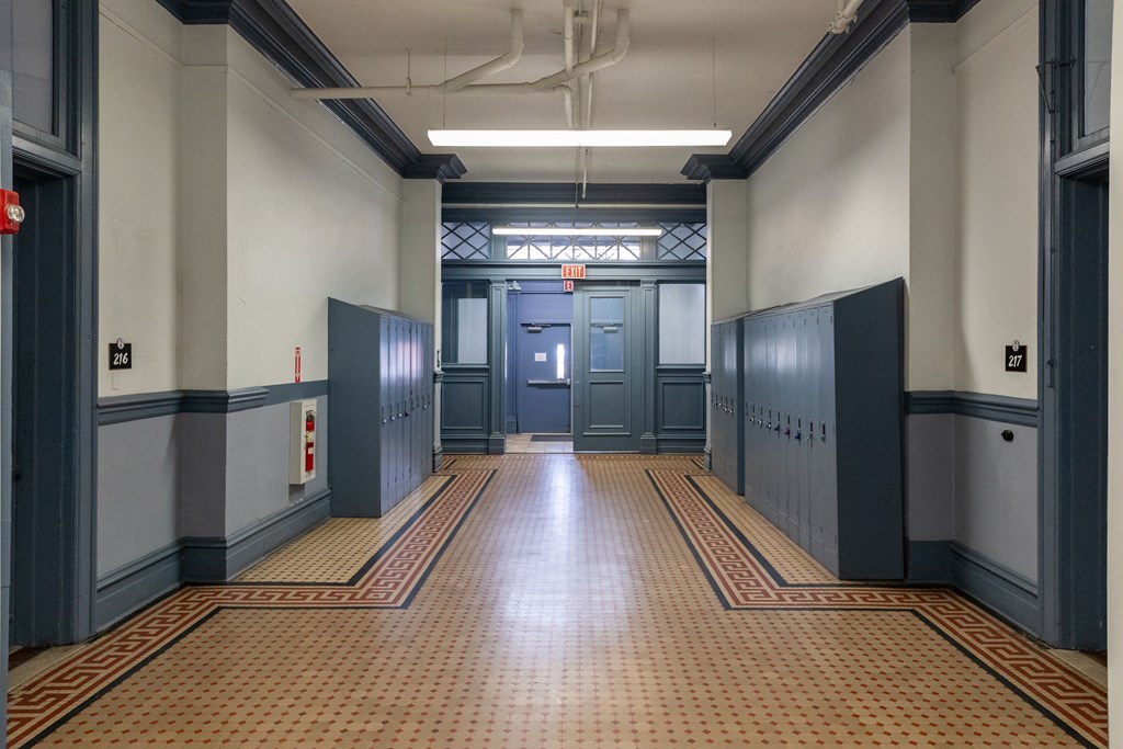 a hallway in a building with blue doors and a tiled floor