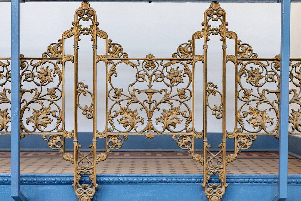 an ornate metal bed frame with gold filigree and blue