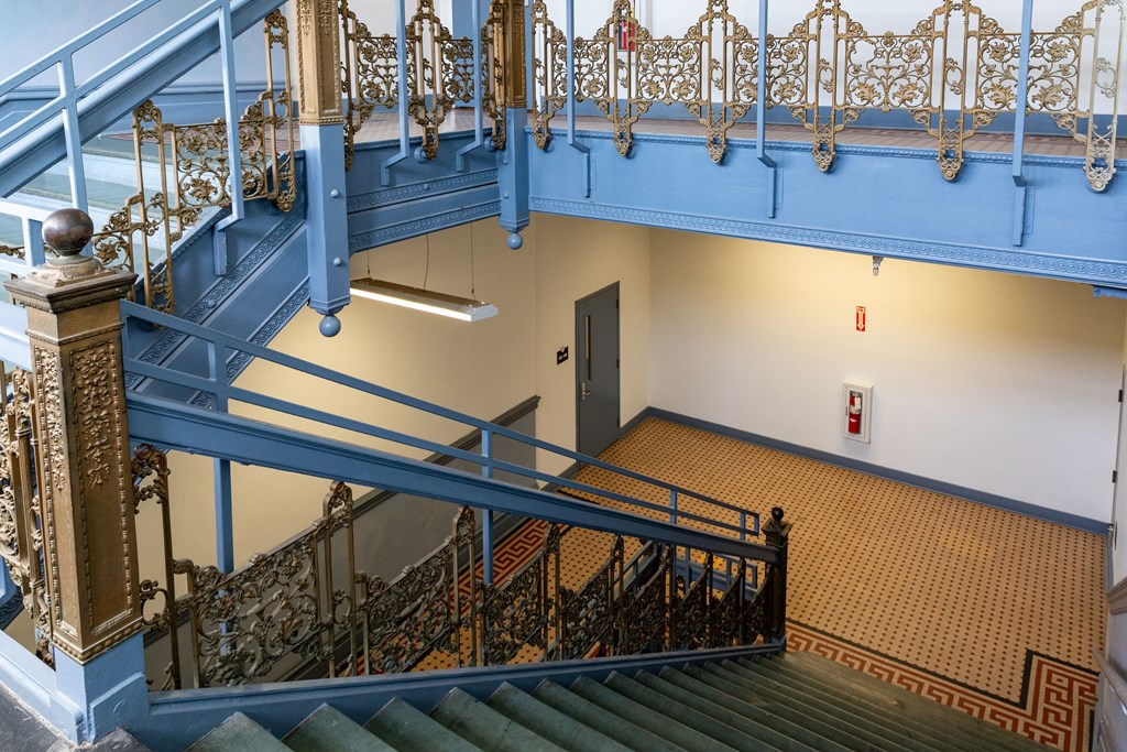 a view of the stairs in a building with blue railing and a door