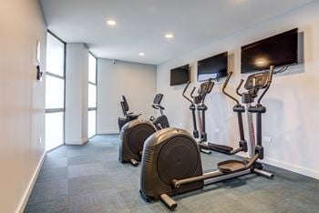 a gym with cardio machines and flat screen televisions