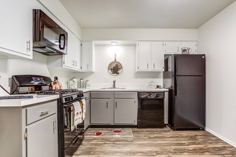 a kitchen with white cabinets and black appliances