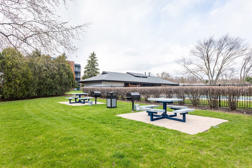 a group of picnic tables in a grassy area with a building in the background at The Township at St. Charles, St. Charles, IL
