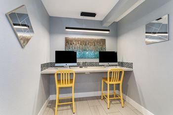 a long desk with two computers and two chairs