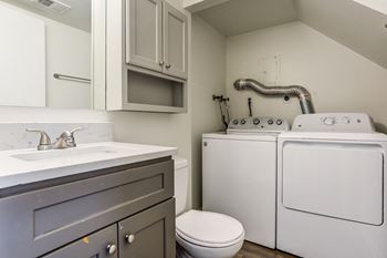 a laundry room with a washer and dryer and a sink and a toilet  at The View Apartments St Charles, St Charles, Illinois