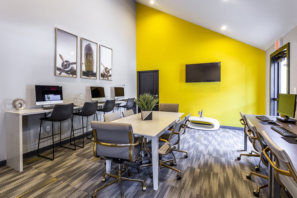 a conference room with a yellow wall and desks and chairs at The Hub at Baton Rouge, Baton Rouge