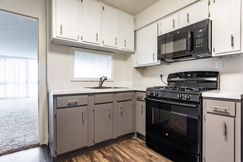 a kitchen with white cabinets and black appliances