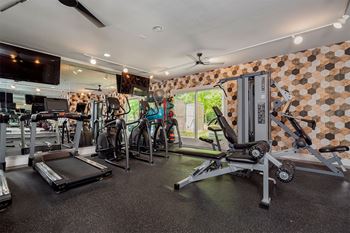 a gym with weights and cardio equipment and a television  at Ascent at Farmington Hills, Farmington Hills, MI