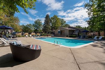a swimming pool with chairs around it and a house in the background  at Ascent at Farmington Hills, Farmington Hills, MI