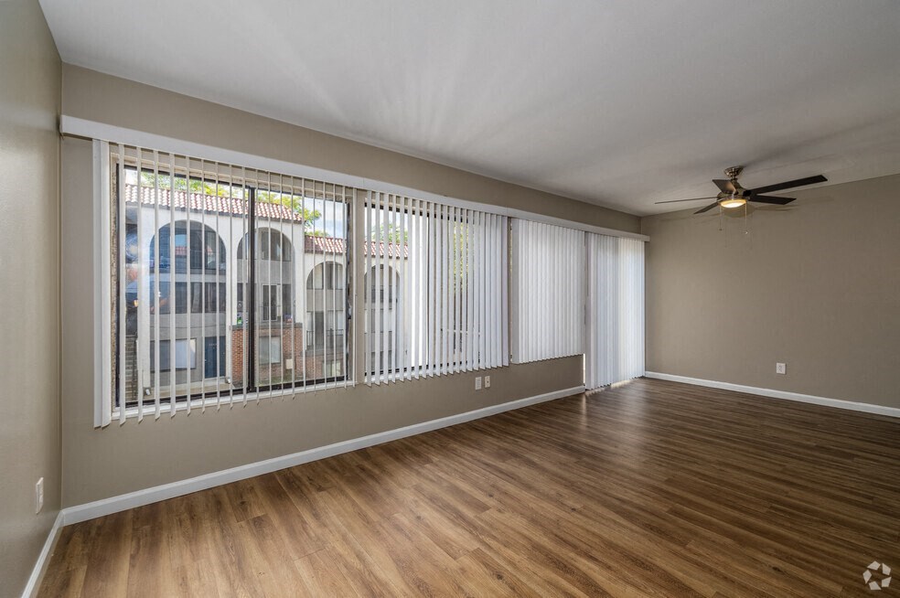 an empty living room with windows and a ceiling fan