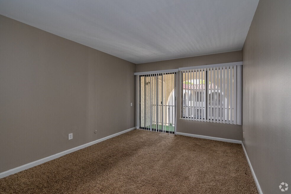 an empty living room with a sliding glass door to a balcony