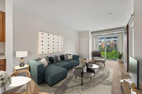 A living room with a grey sofa, a coffee table, a lamp, a painting, and a sliding glass door.
