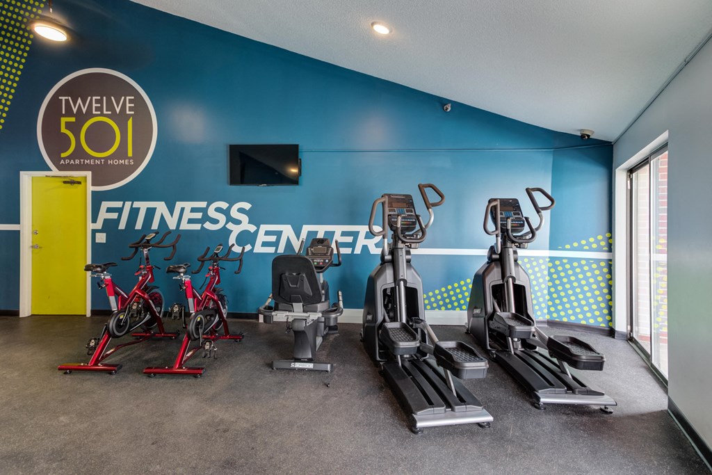 a gym with cardio equipment and a fitness center sign on the wall