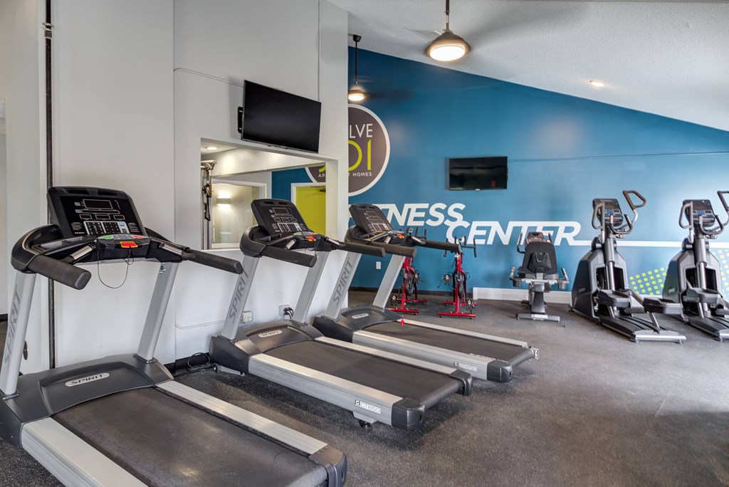 a room filled with cardio equipment and a flat screen tv