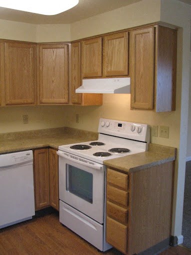 a kitchen with a stove and a microwave and wooden cabinets at Conifer Woods Apartments, Homer, AK