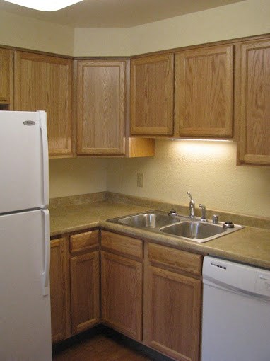 a kitchen with a sink and a refrigerator at Conifer Woods Apartments, Homer, AK, 99603