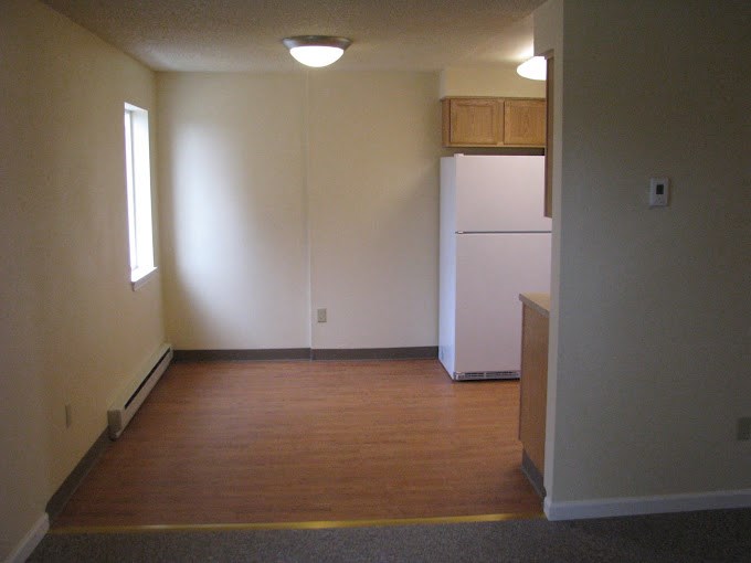 an empty room with a white refrigerator in it at Conifer Woods Apartments, Homer, Alaska