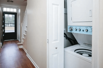 a white kitchen with a washer and dryer and a hallway with a door