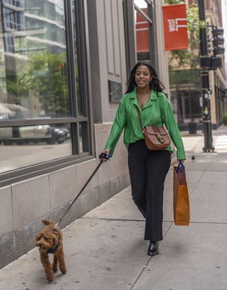 a woman walking her dog on the sidewalk