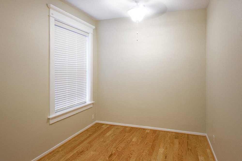 a bedroom with a large window and a wooden floor
