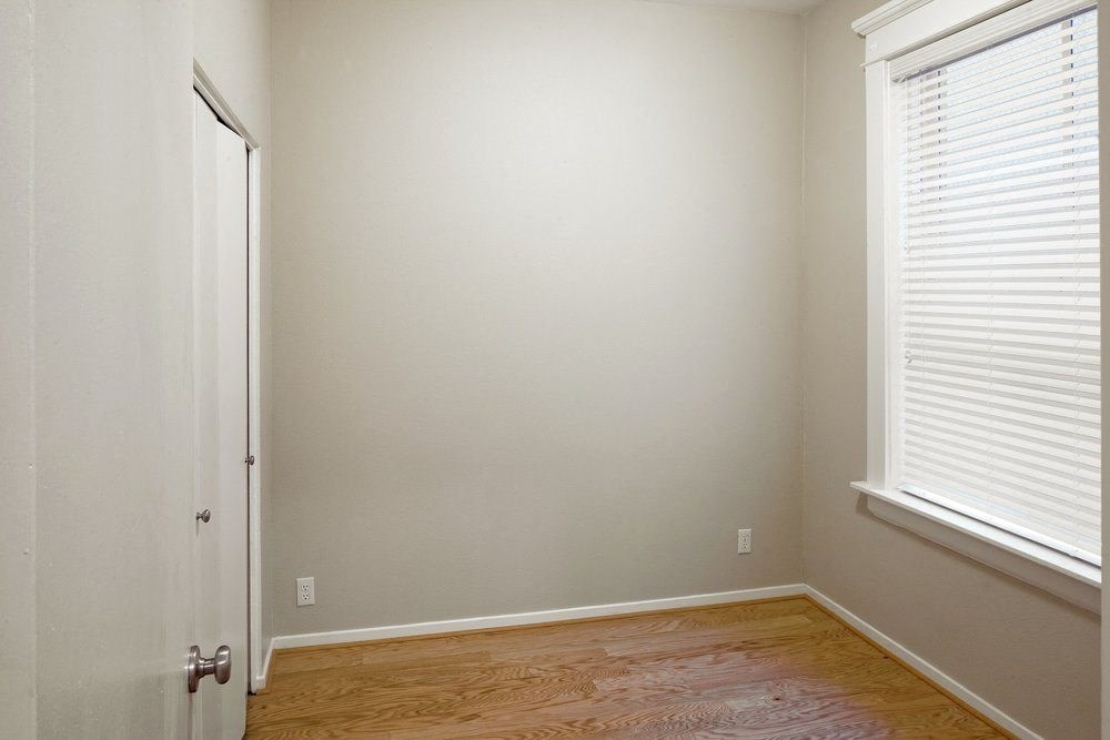 a bedroom with a wooden floor and a window and a door