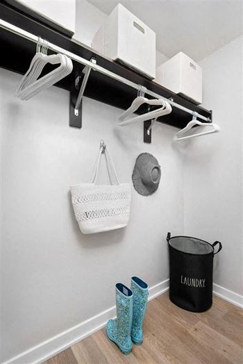 a closet with hooks and a basket and boots on the floor