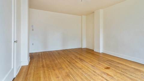 Empty room with wooden flooring and white walls.
