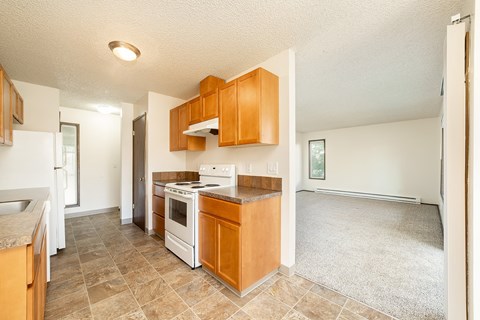 A kitchen with wooden cabinets and a white stove top oven.