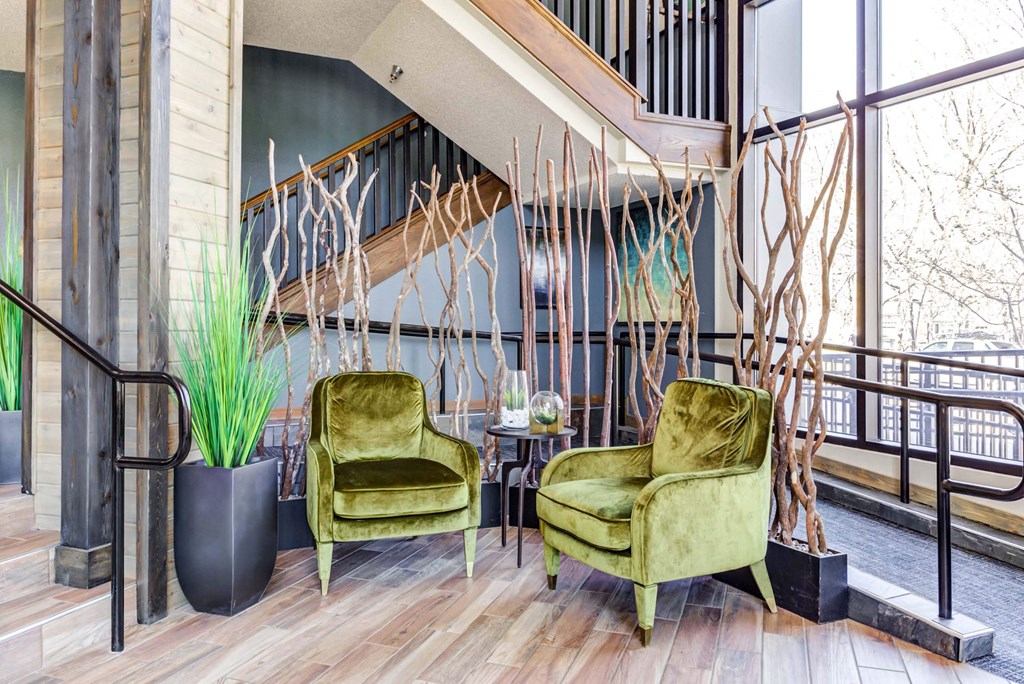 two green chairs in a lobby with a staircase in the background