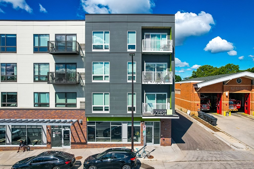 A modern apartment building with a parking lot in front.