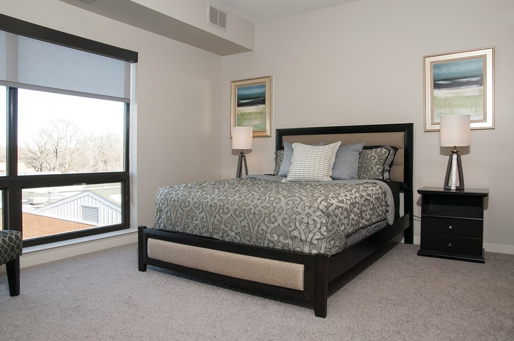 A bedroom with a large bed and two lamps.