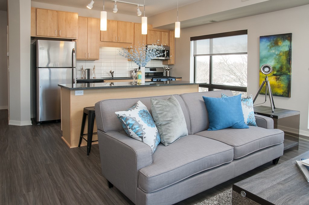 A modern kitchen with a grey couch and a painting on the wall.