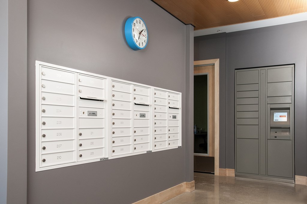 A wall of mailboxes with a clock above them.