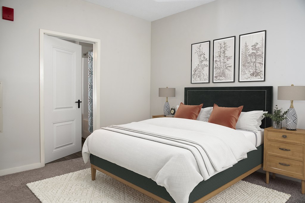 A bedroom with a large bed, a nightstand, and a door.